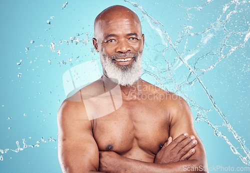 Image of Senior person, water splash and smile portrait of a black man in studio shower for skincare. Spa, blue background and isolated elderly person with happiness for body cleaning and morning dermatology