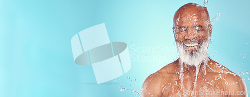 Image of Skincare, water splash and senior man in studio for wellness, beauty or skin treatment on blue background. Happy, elderly and guy model smile, cleaning or facial, hygiene and hydration while isolated