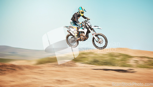 Image of Motorcycle, offroad driving and air jump in desert, blue sky and freedom. Driver, cycling and power stunt on dirt track, competition and motorbike performance on adventure course for fast action show