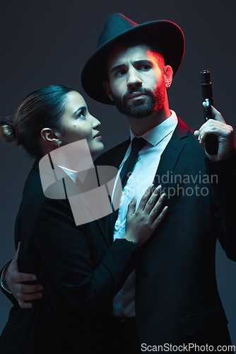 Image of Couple, fashion or gun on dark studio background in secret spy, isolated mafia safety or crime lord security. Gangster love, woman or model with weapon in stylish, trendy or fashion clothes aesthetic