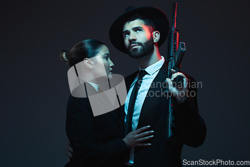 Image of Couple, fashion or weapon on dark studio background in secret spy, isolated mafia safety or crime lord security. Gangster love, woman or model with gun in stylish, trendy or fashion clothes aesthetic