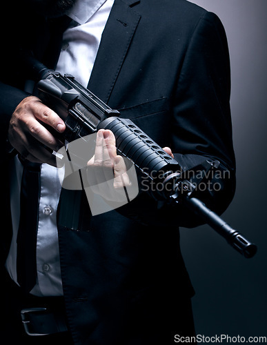 Image of Gangster, hands or holding gun on studio background in dark secret spy, isolated mafia leadership or crime lord security. Model, man or hitman weapon in suit, fashion clothes or bodyguard aesthetic