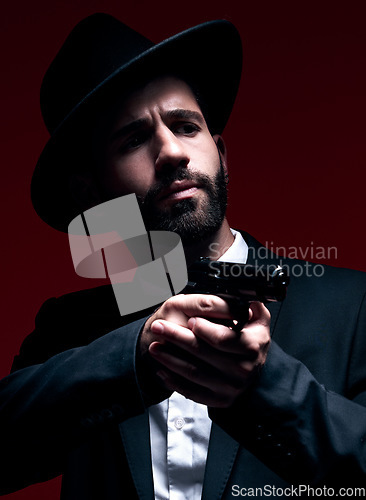 Image of Assassin, suit or shooting weapon on studio background in dark secret spy, isolated mafia leadership or crime security. Model, gangster or hitman gun in aim, formal style or fashion clothes aesthetic