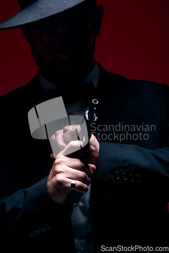 Image of Gangster, hands or cocking gun on studio background in dark secret spy, isolated mafia leadership or crime safety. Model, assassin or hitman weapon in ready, formal style or fashion clothes aesthetic