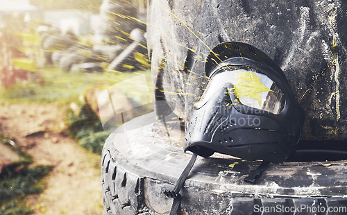 Image of Field, messy and helmet for a game of paintball, sport and battle in Mexico. Safety, military and protective mask on a tire for physical activity, action and competition in nature, woods or forest