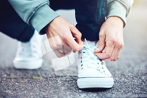 Image of Road, hands and man tie shoes on street to start fitness walk on holiday or vacation outdoors. Travel, wellness and male traveller tying sneakers laces and getting ready for walking, journey or trek.