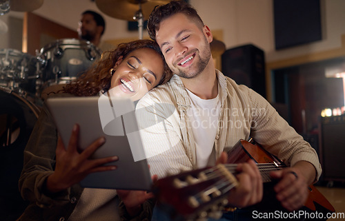 Image of Guitar, music and couple with digital tablet for online lyrics or strumming notes in recording studio. Happy, smile and young man and woman with mobile device and acoustic string instrument at night.