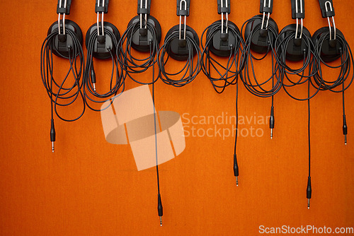 Image of Audio, music and headphones hanging on a wall for a dj, podcast or radio production in the studio. Sound, electronics and equipment for streaming songs, listening to a track or musical accessory