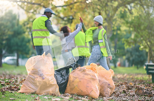 Image of Volunteer, child and people high five while cleaning park with garbage bag for a clean environment. Group or team help with trash for eco friendly lifestyle, community service and recycling in nature