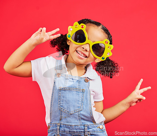 Image of Funny, sunglasses and girl playful, peace and happiness with young person on red studio background. Portrait, mockup and female child with silly eyewear, fun and creative on break, smile and stylish