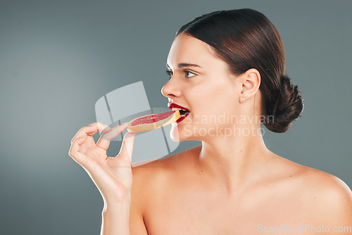 Image of Fruit food, mockup and woman eating a grapefruit for nature and wellness aesthetic in a studio. Model, beauty and natural skincare of a young person with red lipstick hungry for vitamin c nutrition