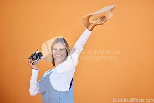Image of Happy woman, photographer and retro camera on an orange wall for advertising vacation, holiday or creativity. Person with a smile and hat for summer travel photography, memory and color background