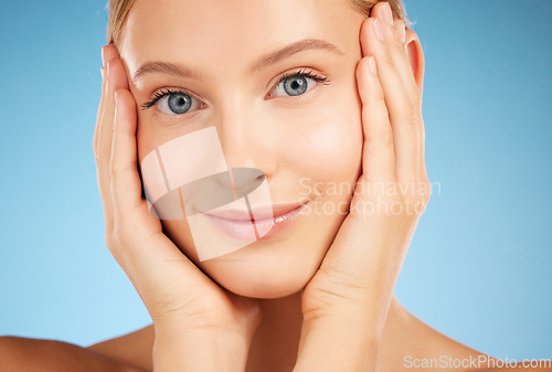 Image of Closeup woman, studio portrait and skincare beauty, natural skin glow and clean aesthetic by blue background. Healthy model, happy and radiant face for cosmetics, hands and facial makeup for wellness