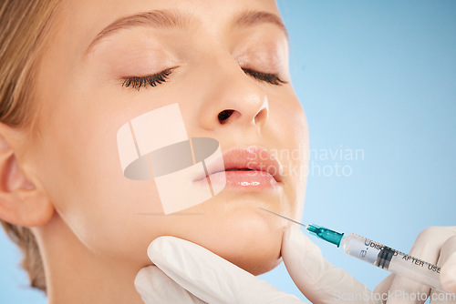 Image of Woman, studio and botox injection for lip filler, beauty and anti aging skincare process by blue background. Model, facial plastic surgery and syringe needle with doctor, surgeon or cosmetic expert