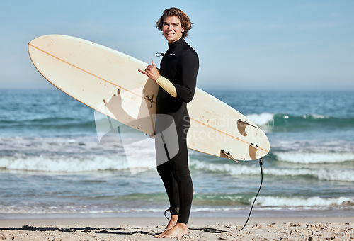 Image of Man, surfer and surfboard at the beach for training exercise or fitness workout in the outdoors. Portrait of happy sports professional with smile showing hand gesture for hang loose ready for surfing