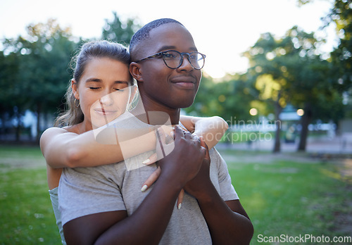 Image of Love, peace or couple of friends hug in a park bonding on a relaxing romantic date in nature together. Interracial, young black man and happy woman embrace enjoying quality time on a holiday vacation