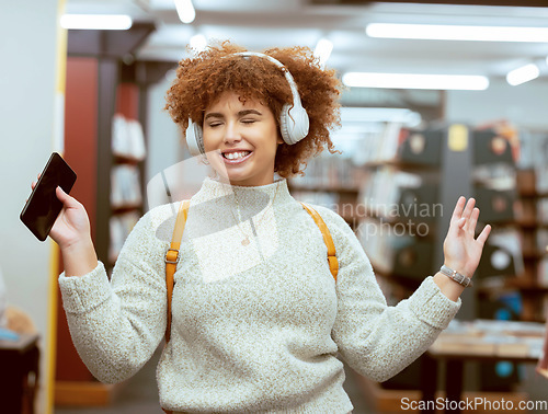 Image of Music, dance and headphones with a student black woman listening to the radio in a university library. Phone, internet and a young female college pupil streaming audio while dancing or having fun