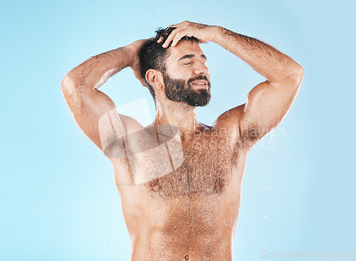 Image of Shampoo, keratin and haircare with a man model cleaning his hair for hygiene in studio on a blue background. Water, wet and treatment with a handsome muscular male washing his head in the bathroom