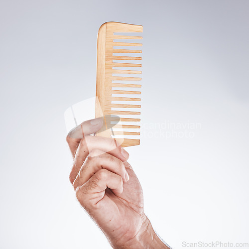 Image of Hand, comb and haircare with a man barber in studio on a gray background for grooming or hair styling. Salon, bamboo and beauty with a male hairdresser holding a tool to groom or style closeup indoor