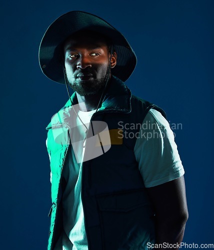 Image of Fashion, shadow and black man model in a studio with a cool, stylish and casual outfit with lighting. Edgy, style and trendy fashionable African male posing while isolated by a blue background.