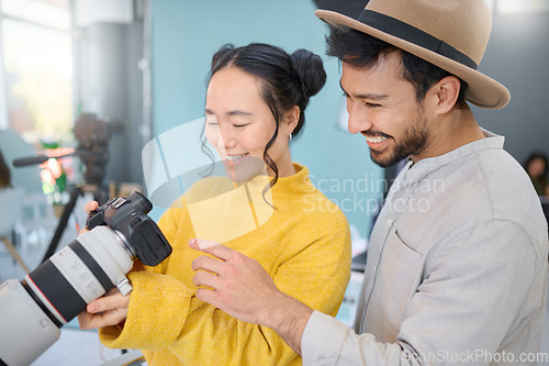 Image of Creative, photography and photographer talking to a model while looking at pictures on a camera. Discussion, photoshoot and young cameraman choosing a image with a woman in a creative artistic studio