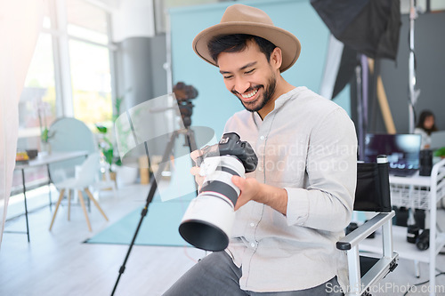Image of Happy, photographer and man with camera in studio, smile and excited before a photo shoot. Backstage, photography and asian guy relax during profession, shooting for design and creative career