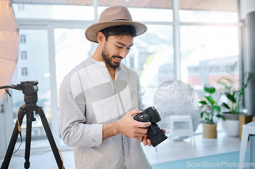 Image of Photographer, camera and man in studio for catalog, selection and photo, happy and photo shoot. Backstage, photography and professional asian male choosing picture for fashion, magazine and creative