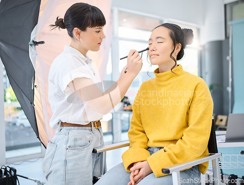 Image of Beauty, makeup artist and model doing makeup on a for a creative photoshoot in a studio. Cosmetics, art and beautician preparing a young Asian woman with a cosmetic routine for a photography job.