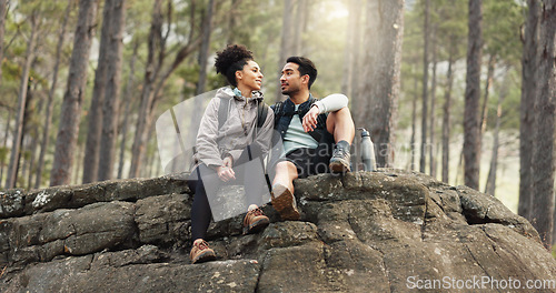 Image of Nature, hiking and a couple relax on adventure trail in forest and sitting on a rock. Health, happy man and woman pointing at natural landscape while relaxing in woods with trees, fitness and freedom