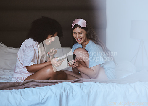 Image of Woman, friends and phone with smile for social media, networking or funny meme on bed together at home. Happy women smiling, laughing and relaxing for post or smartphone entertainment in the bedroom