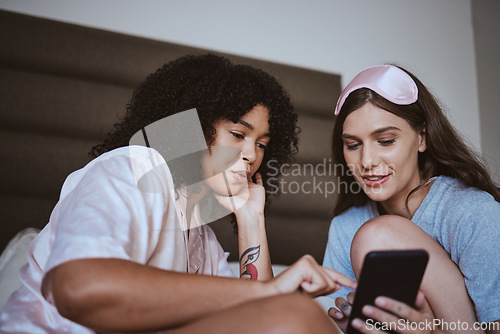 Image of Phone, sleepover and friends in bed talking, bonding and networking on social media, mobile app or internet. Fun, technology and women browsing on a website with a cellphone in a bedroom at home.