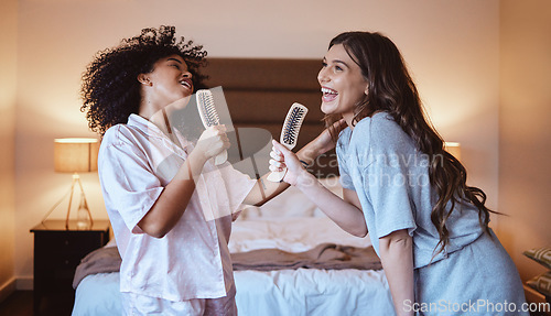 Image of Friends, singing with brush and women in bedroom to get ready for girls night out dancing, fun music concert and happiness. Girl, friend and happy smile, girlfriends grooming at sleepover in pajamas.