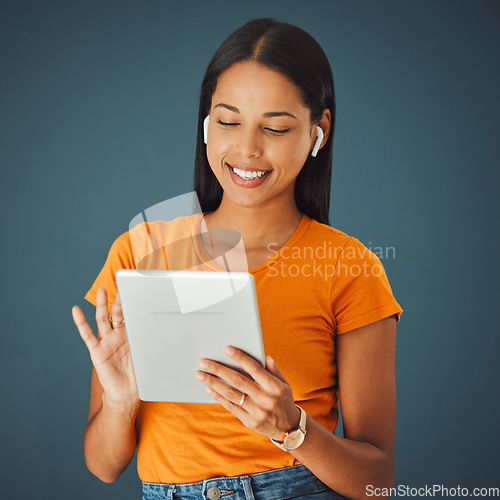 Image of Woman, tablet and listening to music online while streaming and happy on a studio background. Smile of a young gen z person with mobile app for podcast, radio or audio with network internet to relax