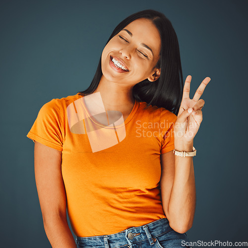Image of Happy woman with smile, peace hand sign and Gen z youth, freedom and fashion isolated on studio background. Happiness, mindset and v emoji, beauty with young person, eyes closed and care free