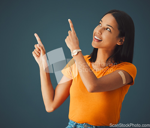 Image of Woman, hands and pointing in studio for covid, vaccine and healthcare with mockup, space and grey background. Health, girl and model with plaster for corona, shot and immunity or isolated copy space