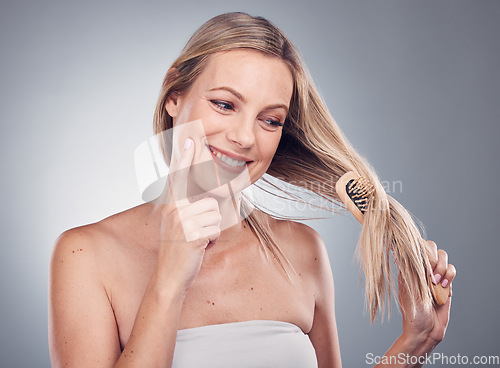 Image of Hair care, thinking and woman brushing her hair in a studio for a keratin, brazilian or botox hair treatment. Pensive, beauty and female model with a brush for a hair style by a gray background,