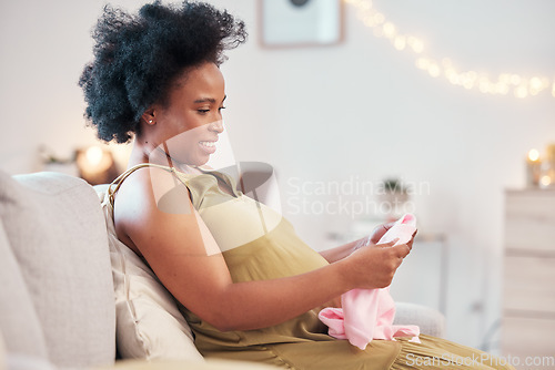 Image of Happy, prepare and pregnant woman with clothes for a baby, gift and happy with clothing for child. Mother, smile and African girl with fashion for a kid during pregnancy on the living room sofa