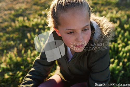 Image of Nature, summer and girl sitting on the grass in a park after playing alone on vacation or weekend trip. Natural, beautiful and child having fun and enjoying in an outdoor field on holiday in Canada.