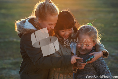 Image of Friends, girls outdoor and smartphone for connection, online games and happiness on summer break. Young people, female children and kids with cellphone, bonding and watching funny videos on field