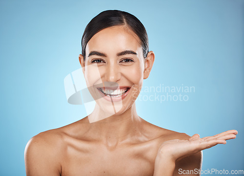 Image of Face, beauty skincare and woman with product placement in studio isolated on a blue background. Makeup portrait, cosmetics and female model with marketing, advertising or branding space for mockup.