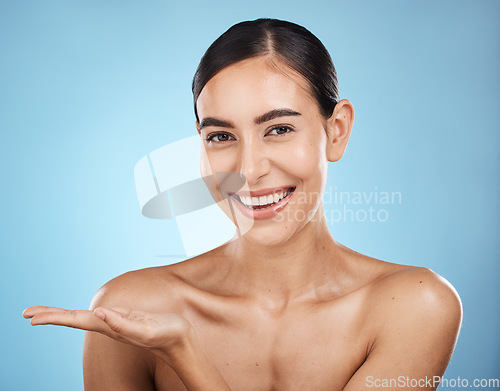 Image of Portrait, beauty skincare and woman with product placement in studio isolated on a blue background. Face makeup, cosmetics and female model with marketing, advertising or branding space for mockup.