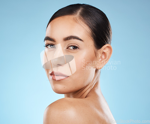 Image of Portrait, shoulder and skincare with a model woman in studio on a blue background for natural beauty. Face, skin and cosmetics with an attractive young female posing to promote a luxury product