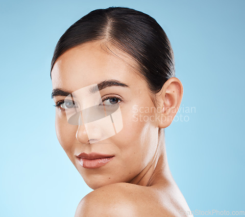 Image of Portrait, beauty and skincare with a model woman in studio on a blue background for natural treatment. Face, skin and cosmetics with an attractive young female posing to promote a luxury product