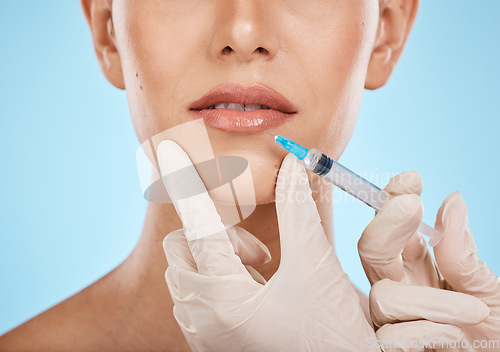 Image of Closeup, woman and needle on lips for cosmetics, dermatology and treatment for beauty, wellness and against blue studio background. Female, lady and injection for mouth, plastic surgery and skincare