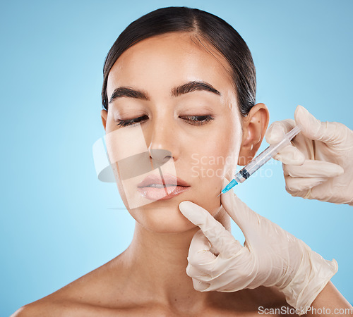 Image of Needle, woman and plastic surgery for skincare, collagen or beauty clinic in studio. Botox cosmetics, face injection and aesthetic filler for body transformation, change and makeup on blue background