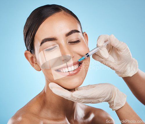 Image of Filler, woman and plastic surgery on lips with needle, skincare or beauty clinic in studio. Botox, face injection and aesthetic cosmetics for happy transformation, change and smile on blue background