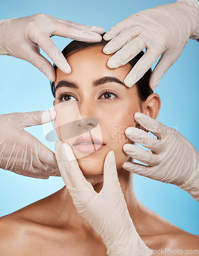 Image of Plastic surgery, check and hands on the face of a woman isolated on a blue background in a studio. Feeling, skincare and doctors touching a model for a botox, cosmetics or dermatology consultation