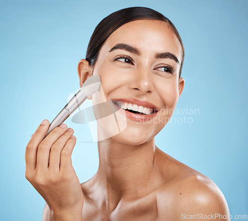 Image of Cosmetics, thinking and woman with a brush for makeup isolated on a blue background in studio. Skincare, beauty and model happy about cosmetology, foundation and body health on backdrop with a smile