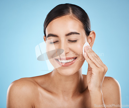 Image of Skincare, cotton pad and woman in a studio with a cosmetic, natural and facial treatment. Self care, beauty and happy female model with a healthy face or skin routine isolated by a blue background.