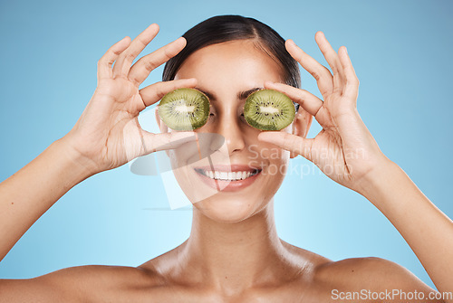 Image of Beauty, skin care and woman with kiwi fruit face for dermatology, natural cosmetic and wellness. Aesthetic model person for sustainable facial glow, nutrition diet and healthy smile blue background